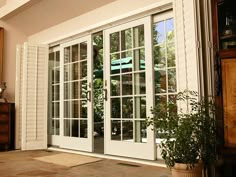 an open patio door with white shutters and potted plant in the foreground