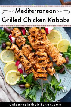 grilled chicken kabobs on a plate with lemon wedges and garnishes