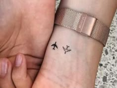 two people holding hands with tattoos on their wrists