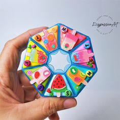 a hand holding a colorful toy with magnets on it's sides and letters in the middle