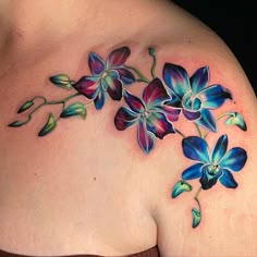 a woman's shoulder with blue and purple flowers painted on the top of it