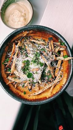 a pan filled with food sitting on top of a table next to a bowl of dip