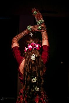 a woman with long hair and flowers in her hair, holding up her hands to the side