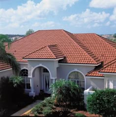 a house with red tile roofing and palm trees