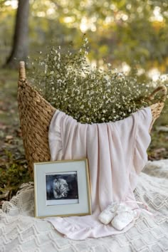 a basket filled with baby's breath flowers next to a framed photo and slippers