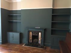 an empty room with a fireplace and bookcases on the wall, painted in green