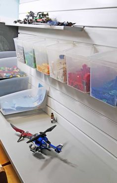 a toy helicopter sitting on top of a white counter next to plastic containers filled with toys