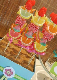 there are many fruit lollipops on the stick in the table with other candies