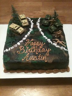 a birthday cake that is decorated with army vehicles and trees on it's side