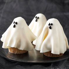 three cupcakes with white frosting and black sprinkles in the shape of ghostes