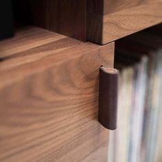 a close up of a wooden shelf with a leather door handle on the bottom half