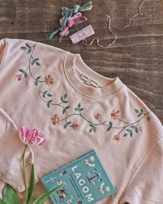 a pink sweater with flowers and a book