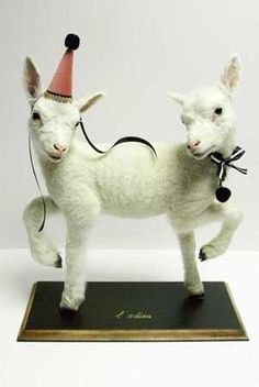 a toy goat with a party hat on it's head standing on a black base