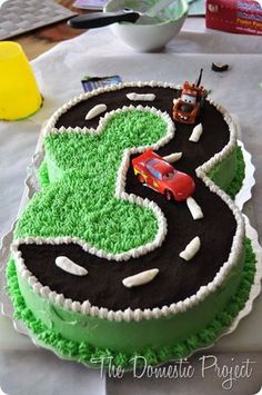 the birthday cake is decorated with cars and trucks