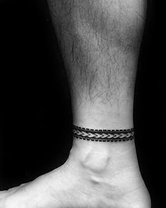 a man's foot with a black and white tattoo on his left ankle,