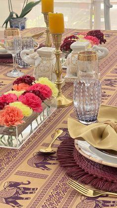 the table is set with candles, plates and flowers in glass vases on it