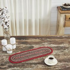 a table topped with a cup of coffee next to a rug and candle holders on top of a wooden table