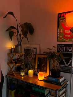 a table with books and candles on it in front of a wall that has posters