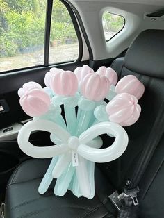 a bunch of balloons sitting in the back seat of a car with bows on them