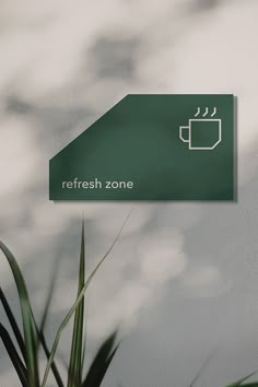 there is a sign that says refresh zone on the side of a wall next to a potted plant