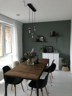 a dining room table with black chairs and a vase filled with flowers on top of it