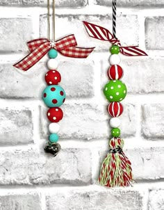 two christmas ornaments hanging on a brick wall next to a red, white and green ribbon