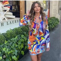 a woman is walking down the street wearing a colorful shirt dress