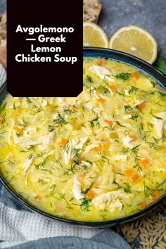 a bowl filled with chicken soup next to sliced lemons and bread on a table