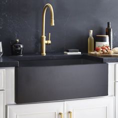 a kitchen with black counter tops and white cabinets, gold faucet handles on the sink