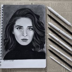 a pencil drawing of a woman's face next to four markers