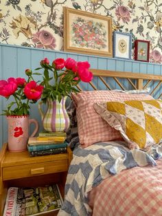 a bed with pink flowers in vases on top of it next to a nightstand