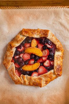 a pie with fruit on it sitting on top of a piece of waxed paper