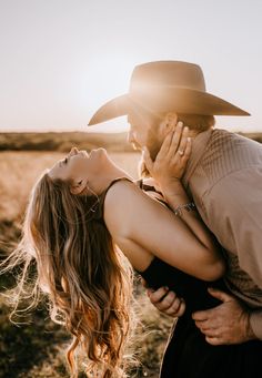 a man and woman kissing in the middle of a field with sun shining on them