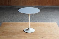 a small white table sitting on top of a wooden platform in an empty room with concrete flooring