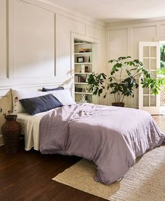 a bed sitting in a bedroom next to a book shelf filled with books and a potted plant