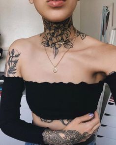 a woman with tattoos on her chest wearing a black off the shoulder top and jeans