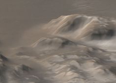 an aerial view of snow covered mountains in the distance with a bird flying over them