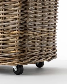 a wicker basket sitting on top of a white table next to a black casteor