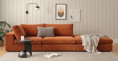 a living room with an orange couch and white rug