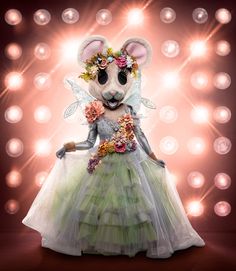 a mouse dressed in a green dress with flowers on it's head and wings