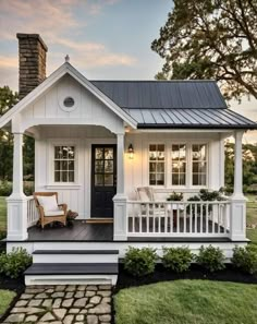 a small white house with black roof and porch