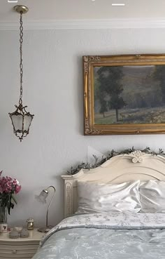 a painting hangs on the wall above a bed with white sheets and blue comforter