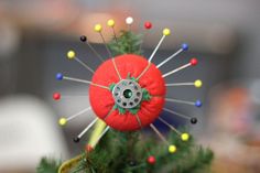 a red pin cushion sitting on top of a green tree