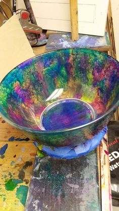 a bowl that is sitting on top of a wooden table in front of some paint