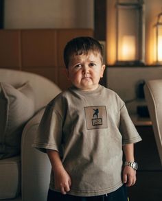 a young boy standing in front of a couch with his mouth open and tongue out