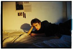 a young man laying on top of a bed