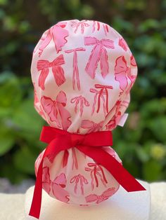 a pink and white hat with red ribbon on it's head, sitting on top of a table