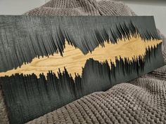 a wooden sound wave art piece sitting on top of a blanket