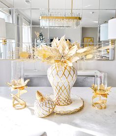 a white and gold vase sitting on top of a table next to two candlesticks