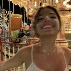 a woman standing in front of a merry go round carousel at night with her eyes closed